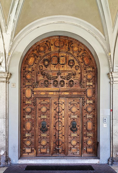 It is a wooden door created by Giorgio Razzani in 1631. It was the main entrance to the hospital known as the Santissimo Crocifisso hospital, built in the mid-15th century in Cesena at the behest of Malatesta Novello. It was rebuilt in 1776-95 by Agostino Azzolini following the original project. In the mid 19th century the palace was rebuilt again and once again this wooden monument is still there!