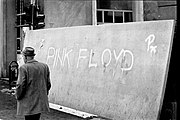 Internationally renowned feature film director and screenwriter Mehmed Fehimović passes a concrete sniper screen whose Pink Floyd graffito reminds him of their "All in all, you're just another brick in the wall."