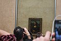 Los visitantes del Museo del Louvre se esfuerzan por lograr una fotografía de La Gioconda con sus teléfonos móviles, en 2013. El cuadro está fuertemente protegido, después de haber sufrido robos y atentados.