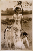 A Chinese woman wearing traditional qipao standing in the bushland with two borzoi dogs in the bushland of Bendigo, Victoria, Australia, 1930.png