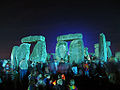 People milling around the floodlit stones