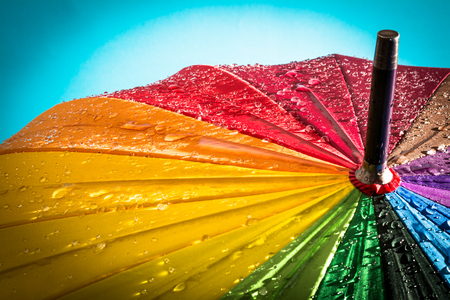 Multi colored colorful umbrella with all colors of the rainbow with raindrops