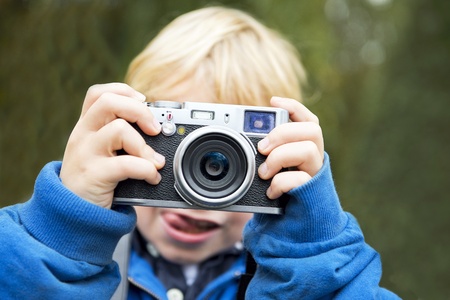 Young photographer holding a retro rangefinder camera in front of his face taking a picture