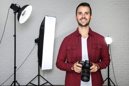 Young photographer with camera and professional studio equipment on grey background Stock Photo