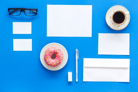 Come up with brand identity blank stationery for branding near coffee and donut on blue background top view mockup pattern copy space Stock Photo