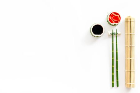 Table served for eating sushi chopsticks bowls with ginger and sause mat on white background top down copy space