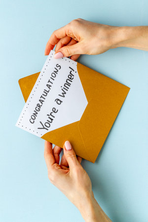 Hände halten Glückwunschkarte im goldenen Umschlag. Text Du bist ein Gewinner in einem Brief
