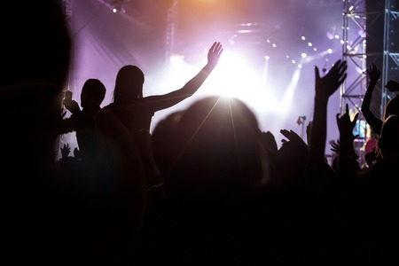 Fans with hands up against a music festival scene