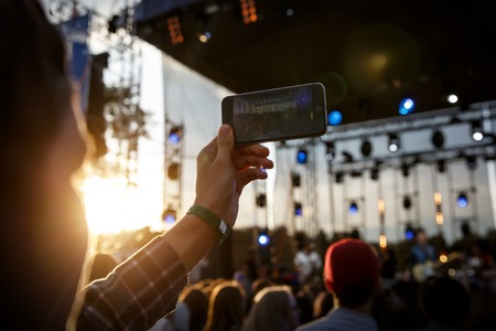 Usando un teléfono móvil en el festival de música de verano al aire libre