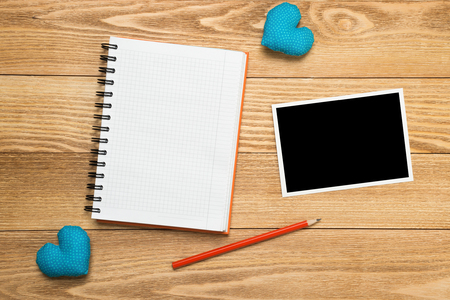 Blank photo frame and notepad on wooden table