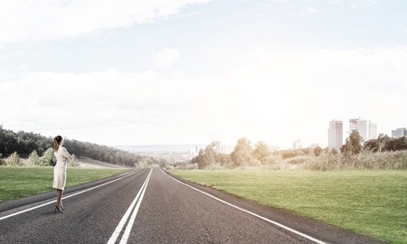 Elegant businesswoman on road standing with back and looking ahead Stock Photo