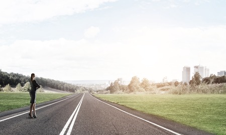 Elegant businesswoman on road standing with back and looking ahead