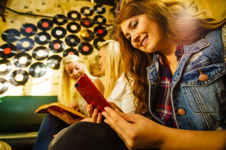 Girl sitting in pub using her smart phone people leisure friendship technology and communication concept