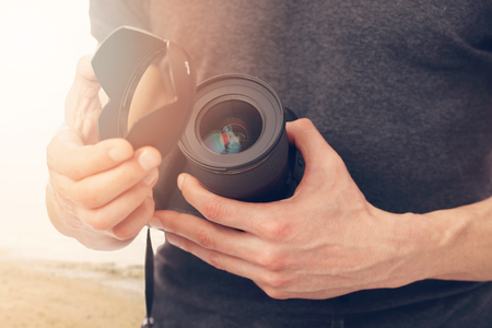 Professional photographer man holding professional digital camera outdoors