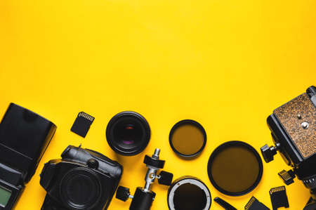 Digital camera lenses and equipment of the photographer on a yellow background