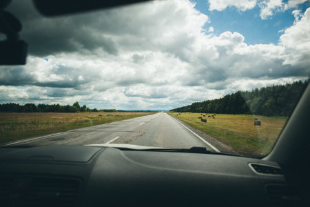 Countryside road with green field and blue sky car driving on highway through rural landscape with forest road trip concept perfect for driving and exploring natural scenery