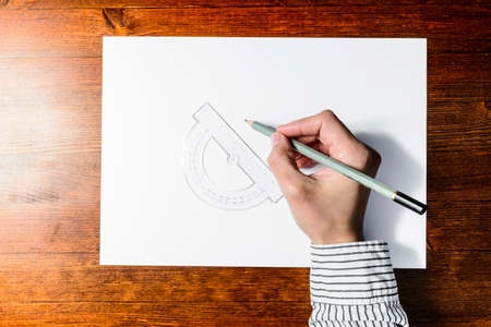 Female hands drawing with a gray pencil on a white paper using a bevel angle