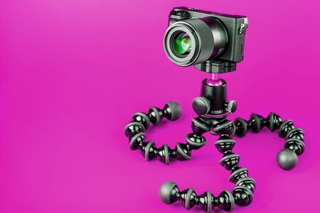 Professional camera on a tripod on a pink background record videos and photos for your blog or report free space isolated