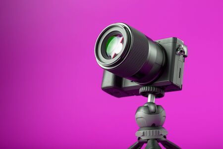 Professional camera on a tripod on a pink background record videos and photos for your blog or report free space isolated