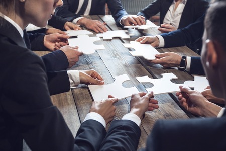 Business people and puzzle on wooden table teamwork concept