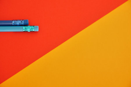 Two blue pens on a red and yellow background top view