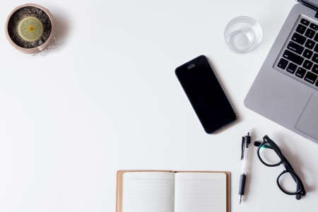 White office desk table with laptop smartphone notebook and glass top view with copy space flat lay