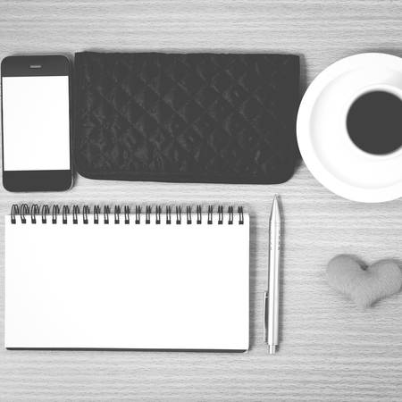 Desktop coffee with phone notepad wallet heart on wood background black and white color