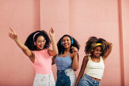 Mujeres felices escuchando música y bailando juntas Foto de archivo