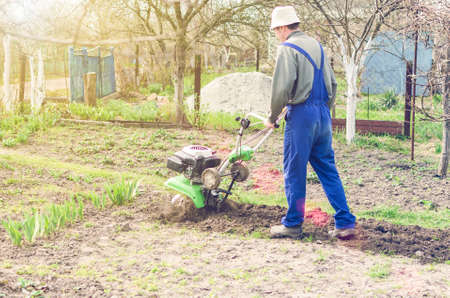 Man working in the spring garden with tiller machine