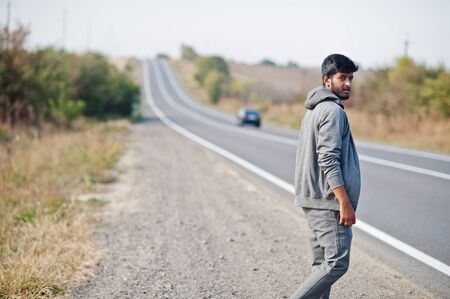Hitchhiking indian man travelling by hitchhike on road side on highway Stock Photo