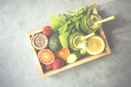 Organic and healthy green smoothie with banana spinach avocado citrus fruits and chia seeds in a glass bottles on a rustic background withcopy space