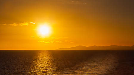 Atardecer Lanzarote. Puesta de sol sobre la costa de la isla canaria española de Lanzarote. Se puede ver un yate pasando bajo el sol en el horizonte.