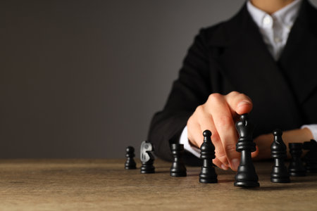 A man in a black suit with chess on the table