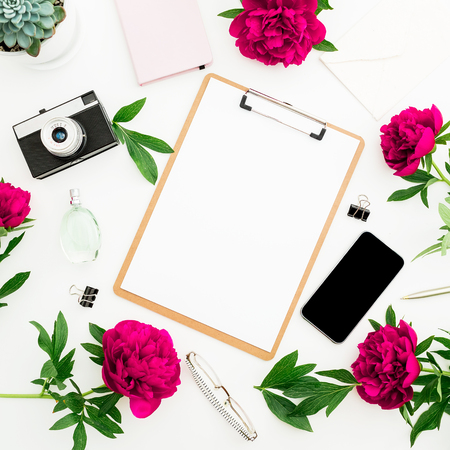 Freelancer workspace with clipboard dairy peony flowers retro camera and smartphone on white background flat lay top view beauty blog concept with copy space Stock Photo