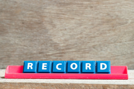 Tile letter on red rack in word record on wood background Foto de archivo