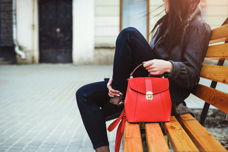 Woman sitting on the bench with red backpack in hands