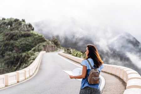 Pretty brunette girl in sunglasses outdoor in the mountains with map Stock Photo