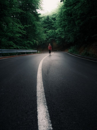 A man is jogging on a road in the forest in the morning Stock Photo