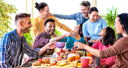 Grupo multiétnico de amigos sentados a la mesa en un bar restaurante con brunch haciendo muecas. gente diversa celebrando un desayuno dulce juntos disfrutando de unas felices vacaciones. concepto de estilo de vida y alegría