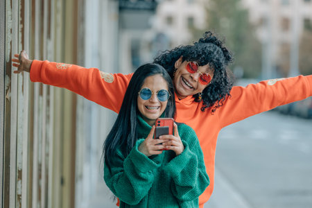 Chicas en la calle con teléfonos grabando en vivo. - 204242892