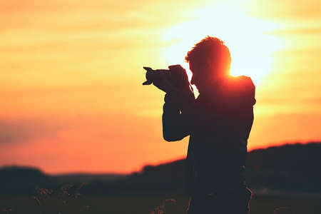 Silhouette of the young photographer at the sunset Stock Photo