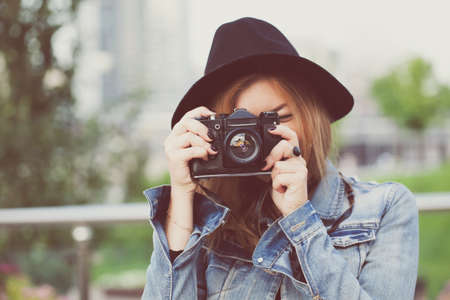 Young girl photographer walking along the street in a jeans jacket with an old camera Stock Photo