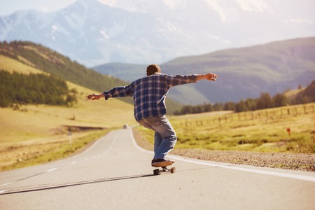 Man skating on longboard straight mountain road Stock Photo