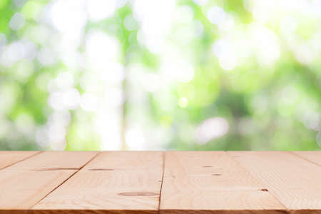 Mesa de madera en blanco con sol y desenfoque de fondo bokeh de árbol verde, maqueta de plantilla para montaje de producto Foto de archivo