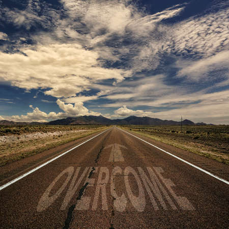 Conceptual image of desert road with the word overcome and arrow Stock Photo