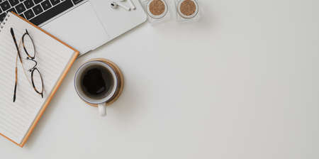 Top view of minimal workspace with laptop computer a cup of coffee and office supplies on white desk background Stock Photo