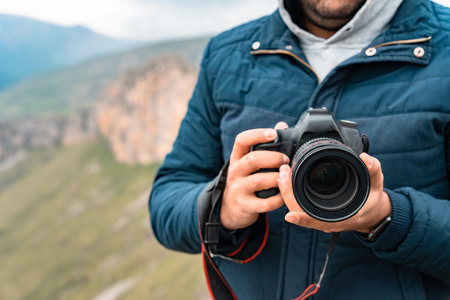 Man holding a camera in his hands in the mountains