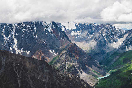 Atmospheric alpine landscape with massive hanging glacier on giant rocks and valley with mountain lakes big glacier tongue low clouds over snowbound mountains majestic scenery on high altitude Фото со стока