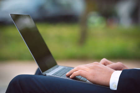 Man working on his laptop outdoors business man hands typing on computer