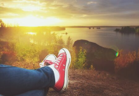 Pernas de viajante sentado no penhasco e relaxante. Conceito de viagem e liberdade